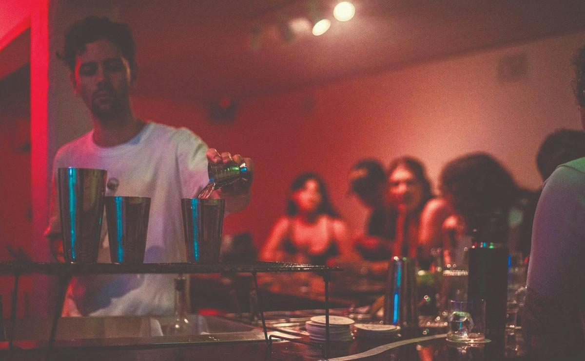 A vibrant scene of a bartender pouring drinks to happy guests