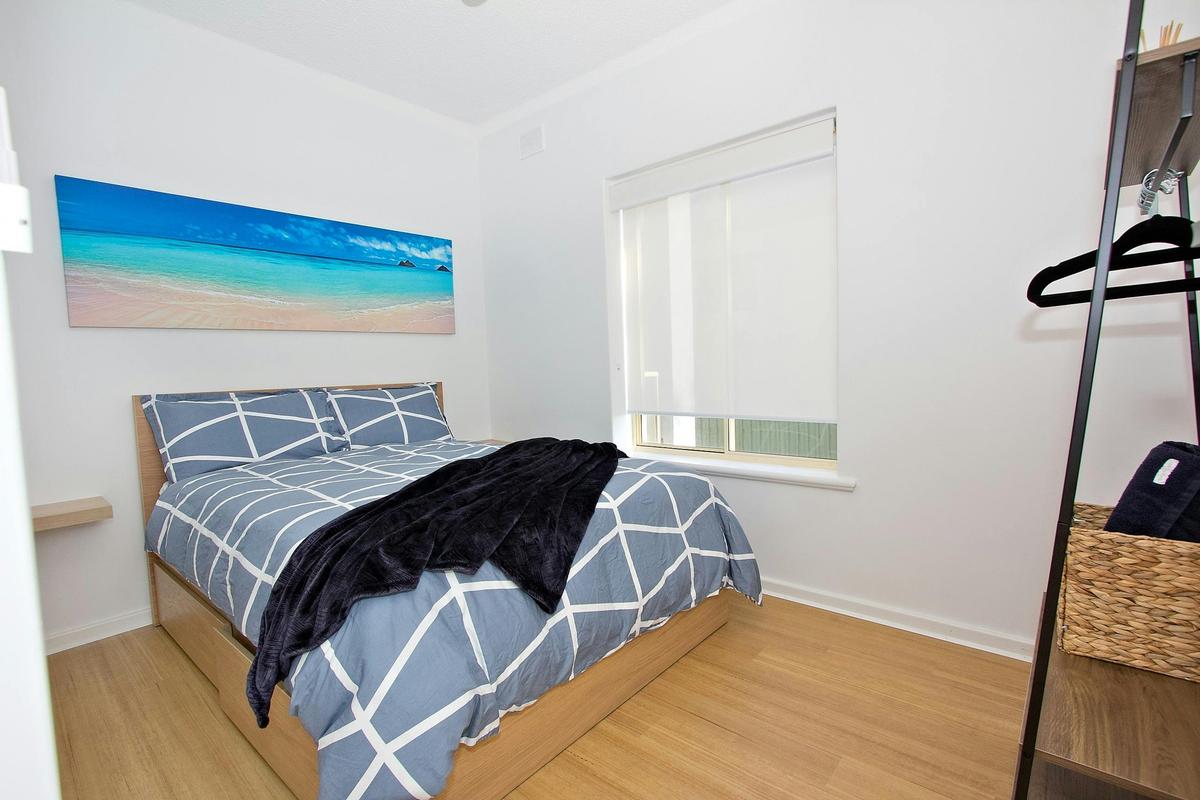 2nd bedroom with a double bed, bedside shelfs, garment rack and an ocean view