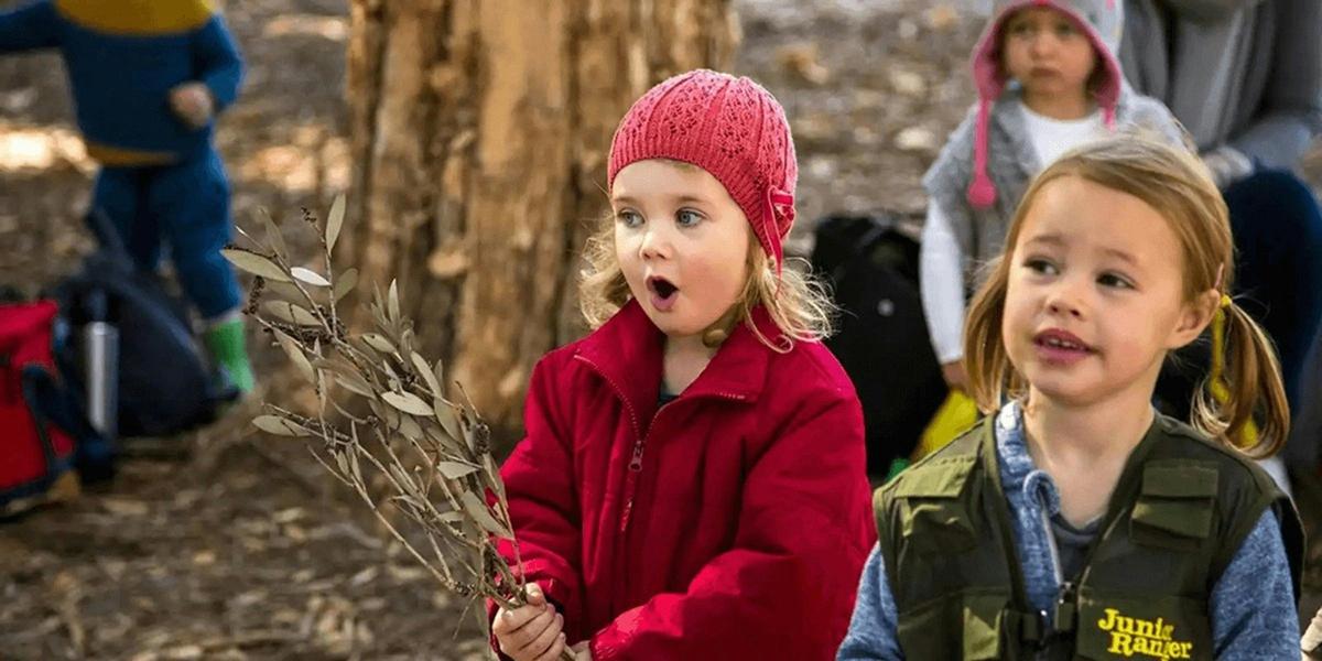 Small child wearing red beanie outside looking surprised or excited