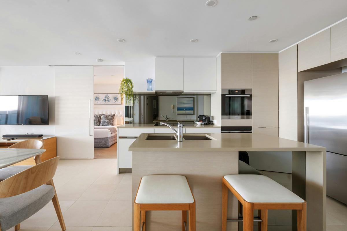 The kitchen has a stone island with seating, wall ovens and a full height fridge.