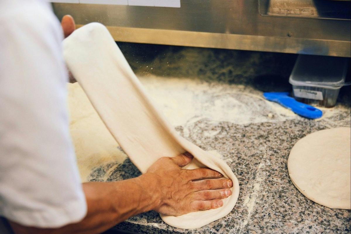 Hand-stretching a pizza base in the kitchen at Il Vigneto Pizzeria