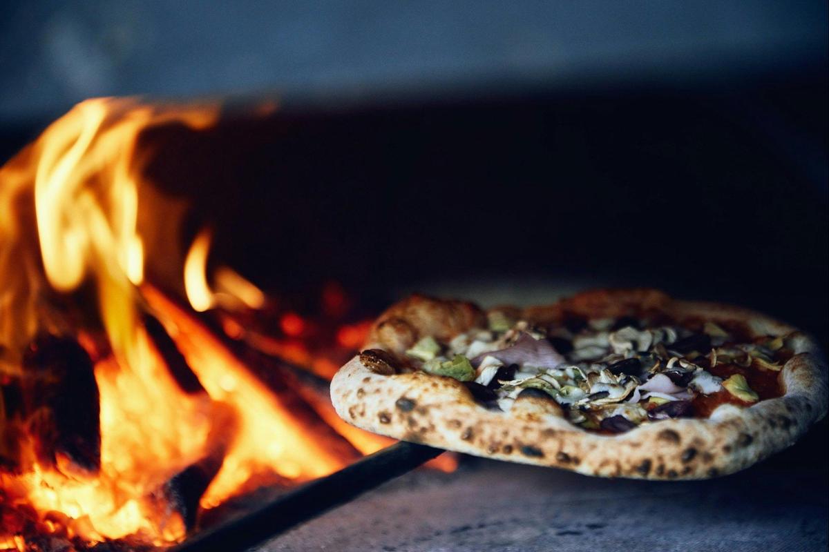 A pizza cooking in the wood-fired oven at Il Vigneto Pizzeria