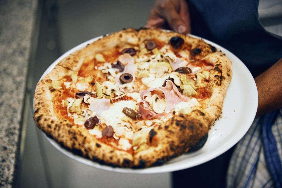 A wood-fired pizza with ham, artichoke, mushroom and olives at Il Vigneto Pizzeria