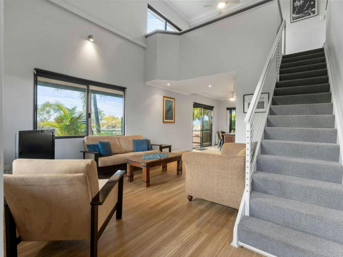 Airy lounge with high ceilings, warm timber floors, and garden views