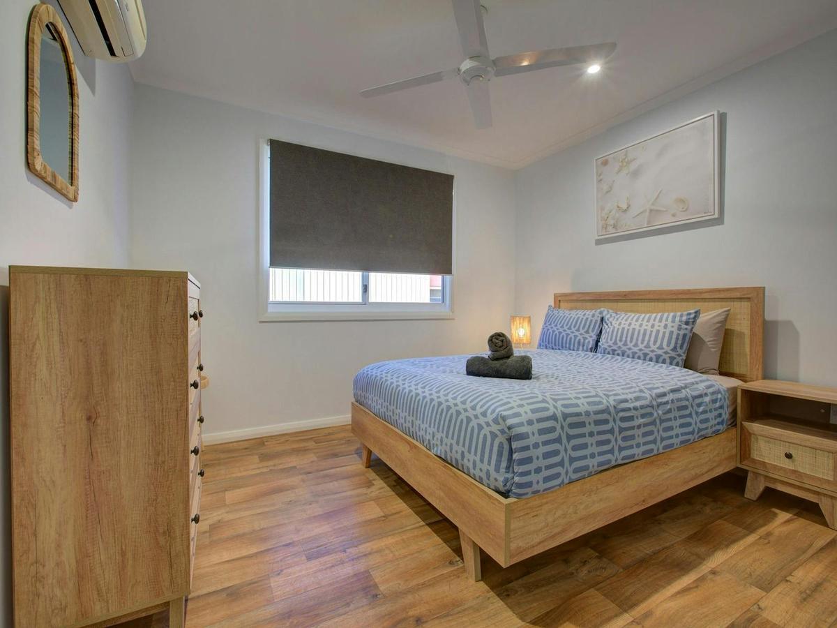 Serene coastal bedroom with a comfortable queen bed and natural timber accents