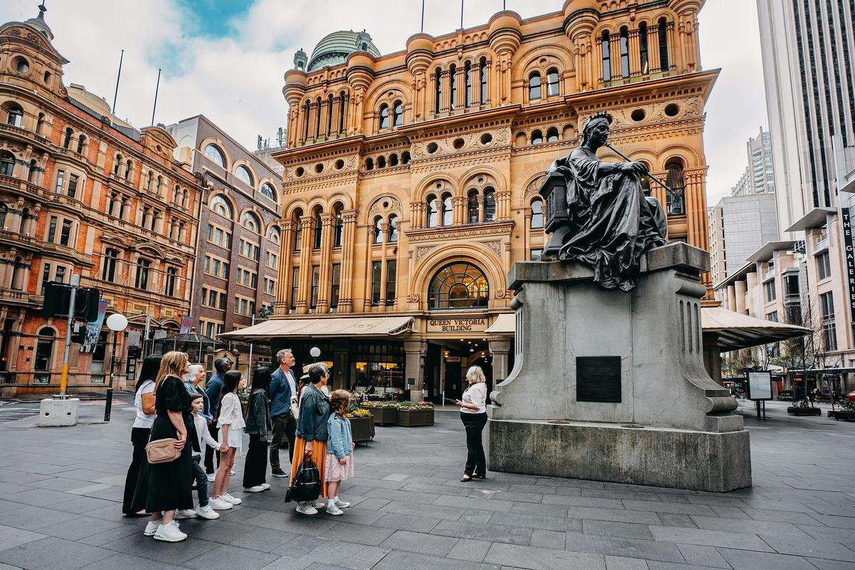 A tour group on the QVB History Tour looking at the Queen Victoria statue outside