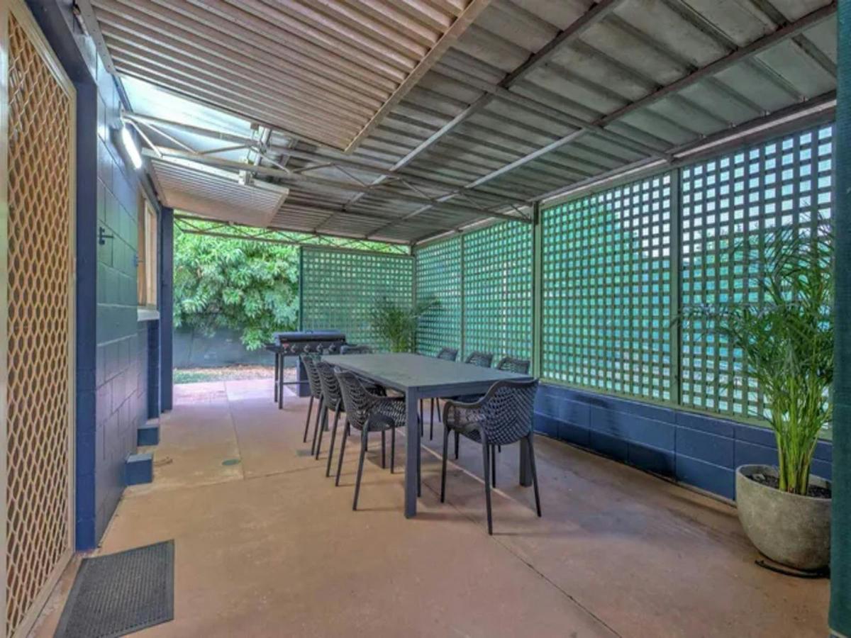 Large covered outdoor dining area with barbecue and leafy garden surrounds