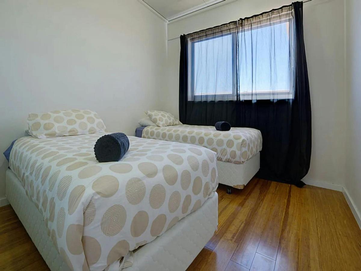 Bright twin bedroom with timber floors and fresh, simple styling