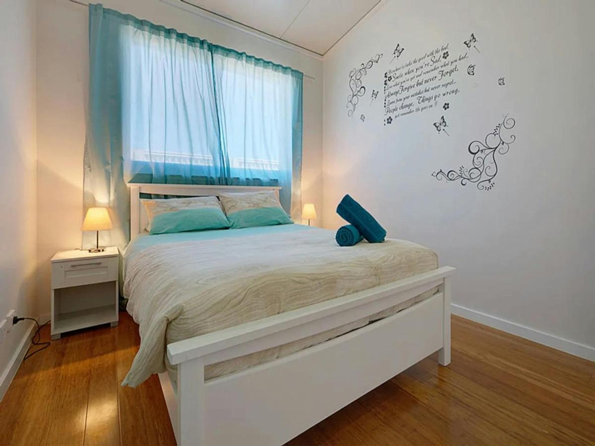 Comfortable queen bedroom with warm timber floors and soft coastal tones