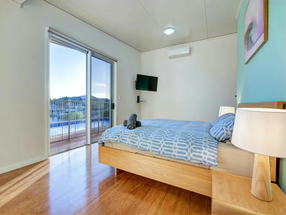 Spacious waterfront bedroom with balcony access, television and air conditioning