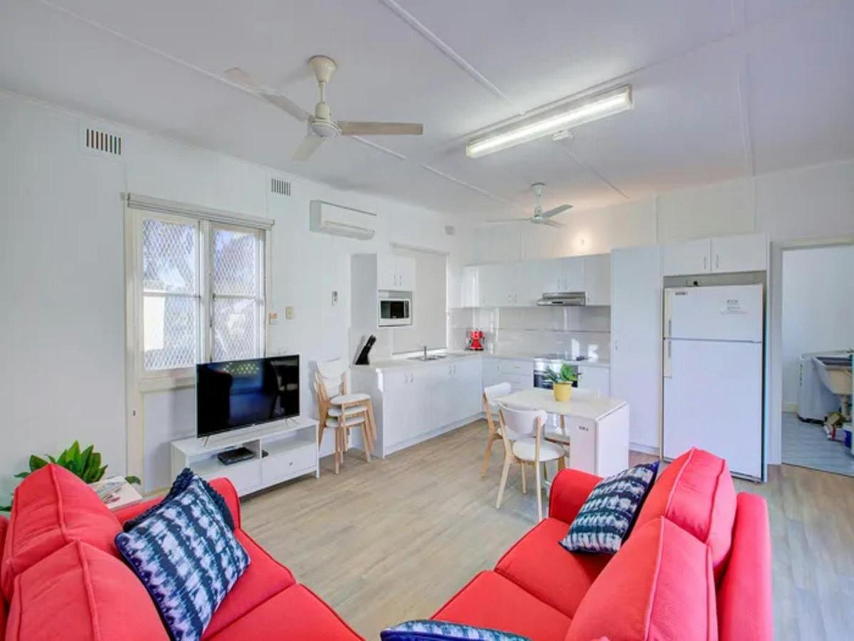 Bright open-plan living and kitchen area with cheerful red seating