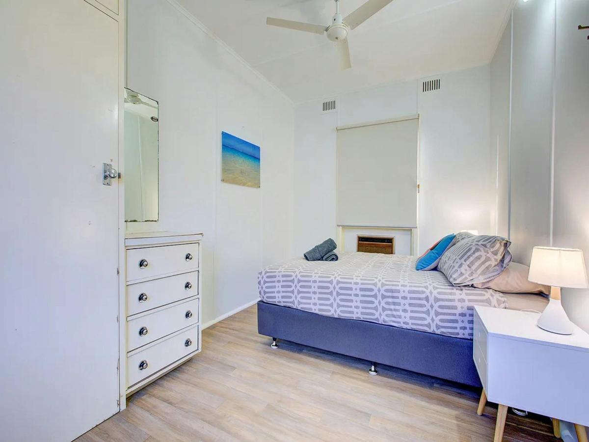 Comfortable queen bedroom with warm timber floors and soft lighting