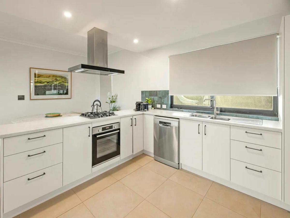 Modern white kitchen with stainless steel appliances and ample storage