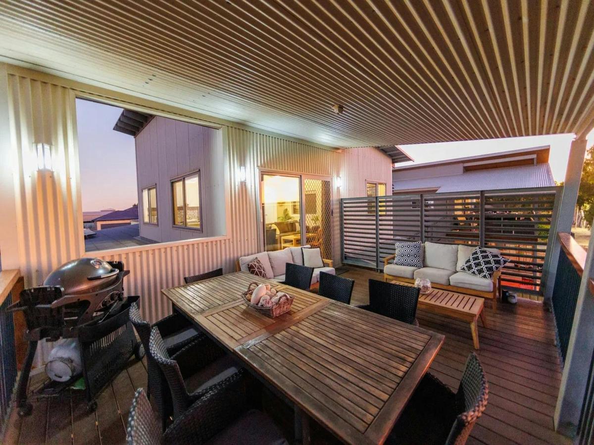 Covered outdoor dining area with lounge seating and a barbecue