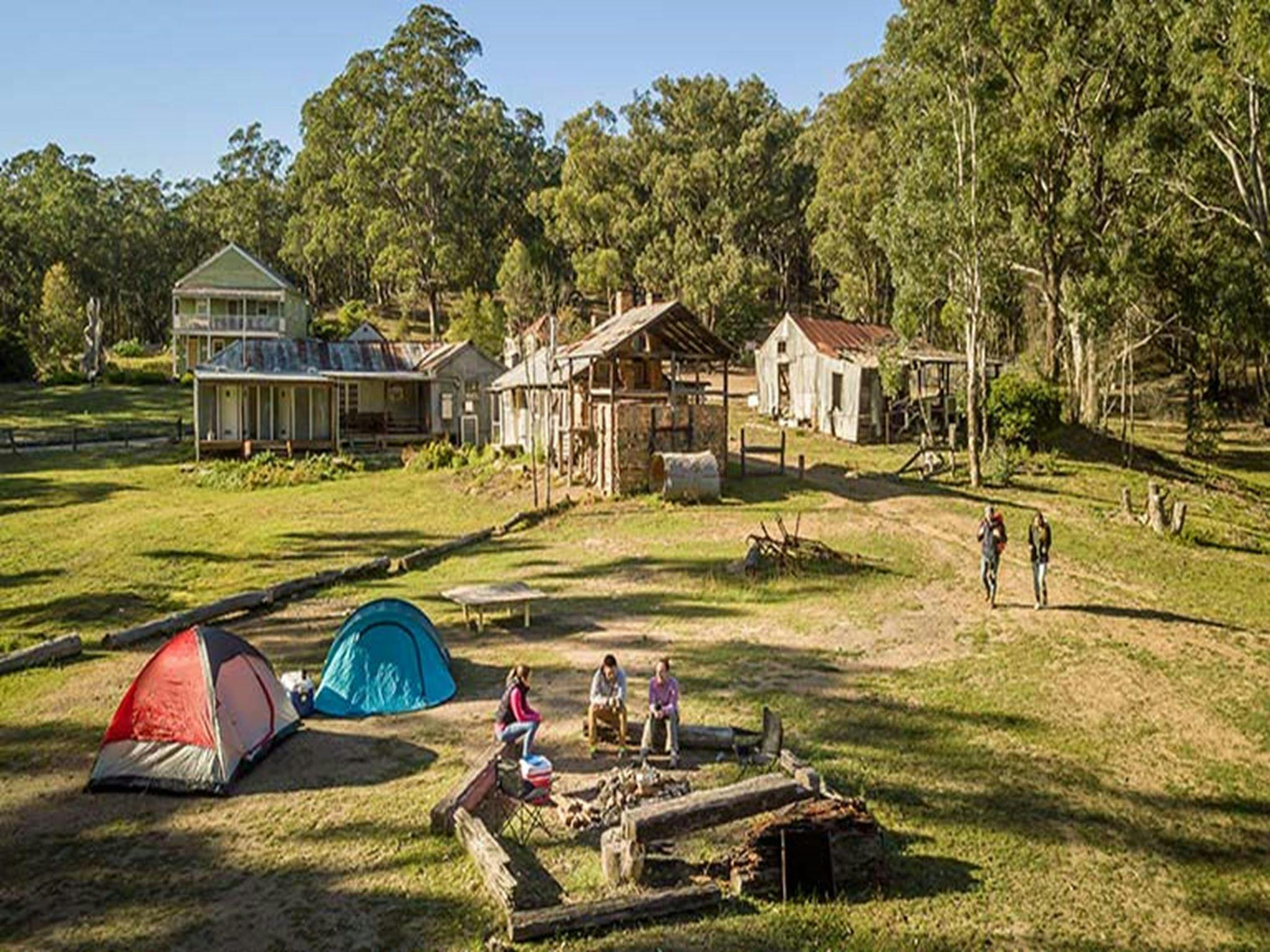 Campers sitting around the fire pit near their tents at Private Town campground in Yerranderie