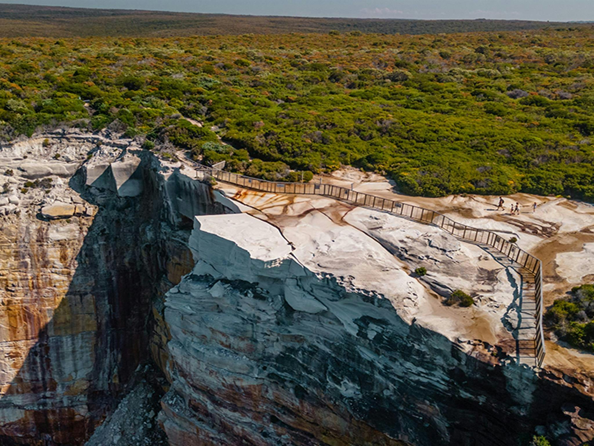 Aerial photo of a cliff with a large safety fence around a section of land to prevent visitors being