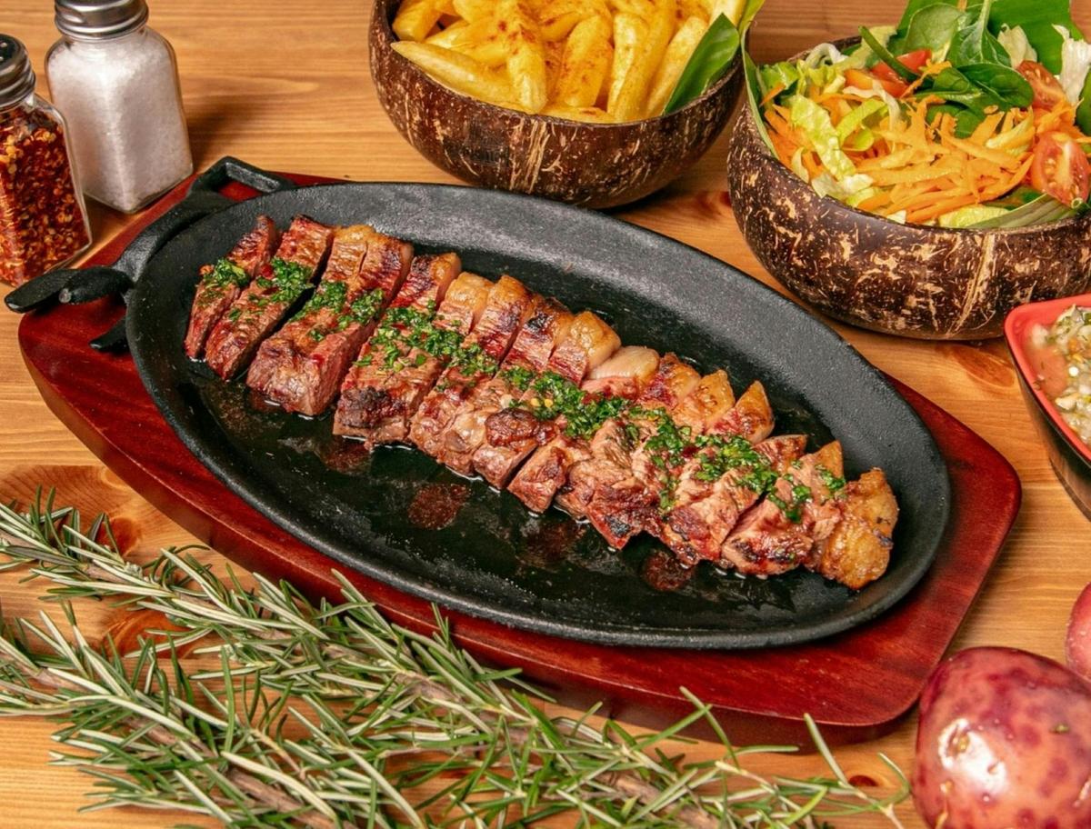 Sliced grilled picanha with herb sauce, fries and mixed salad.