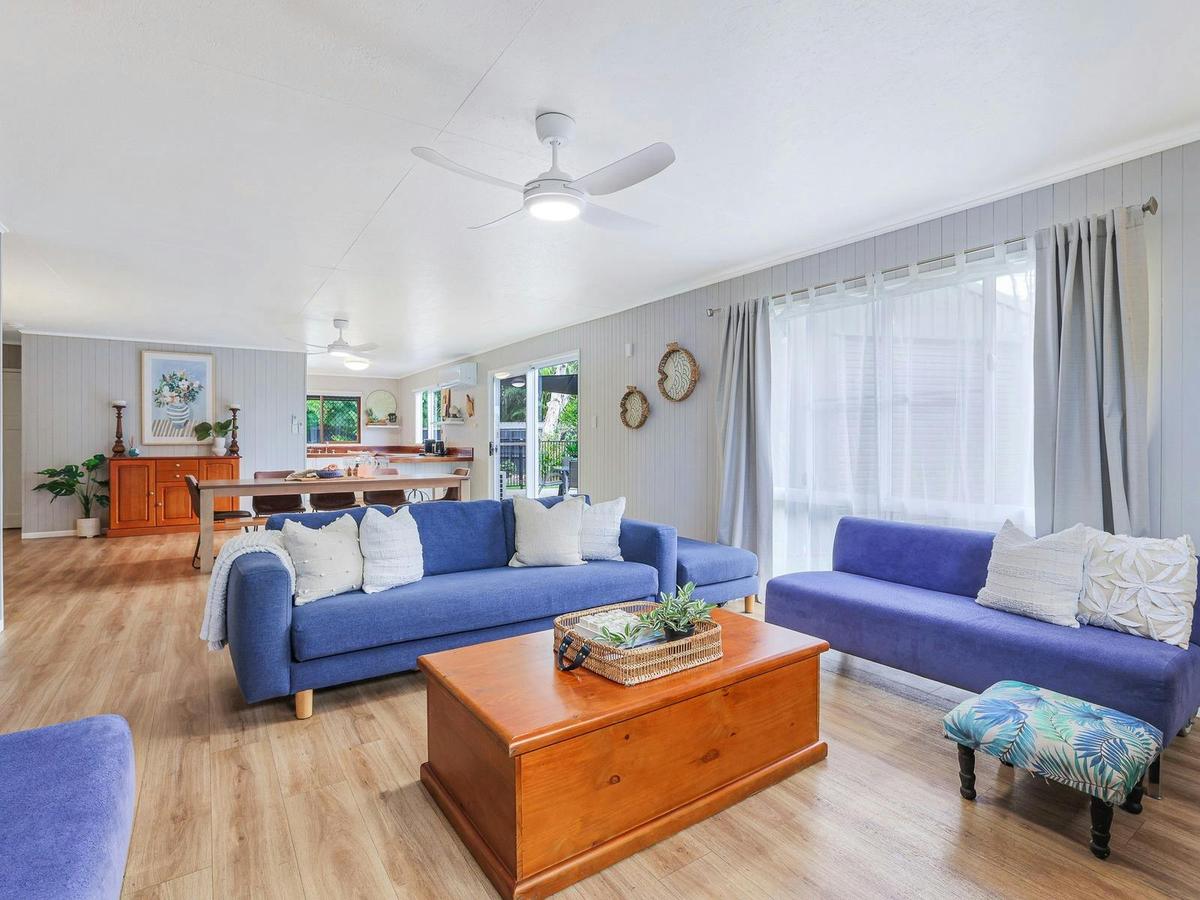 Living room with open kitchen and large dining table. Aircon and ceiling fans