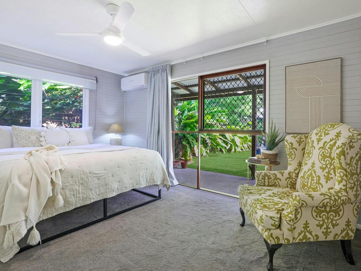 Master bedroom with a view of the back yard, king bed, tv and aircon