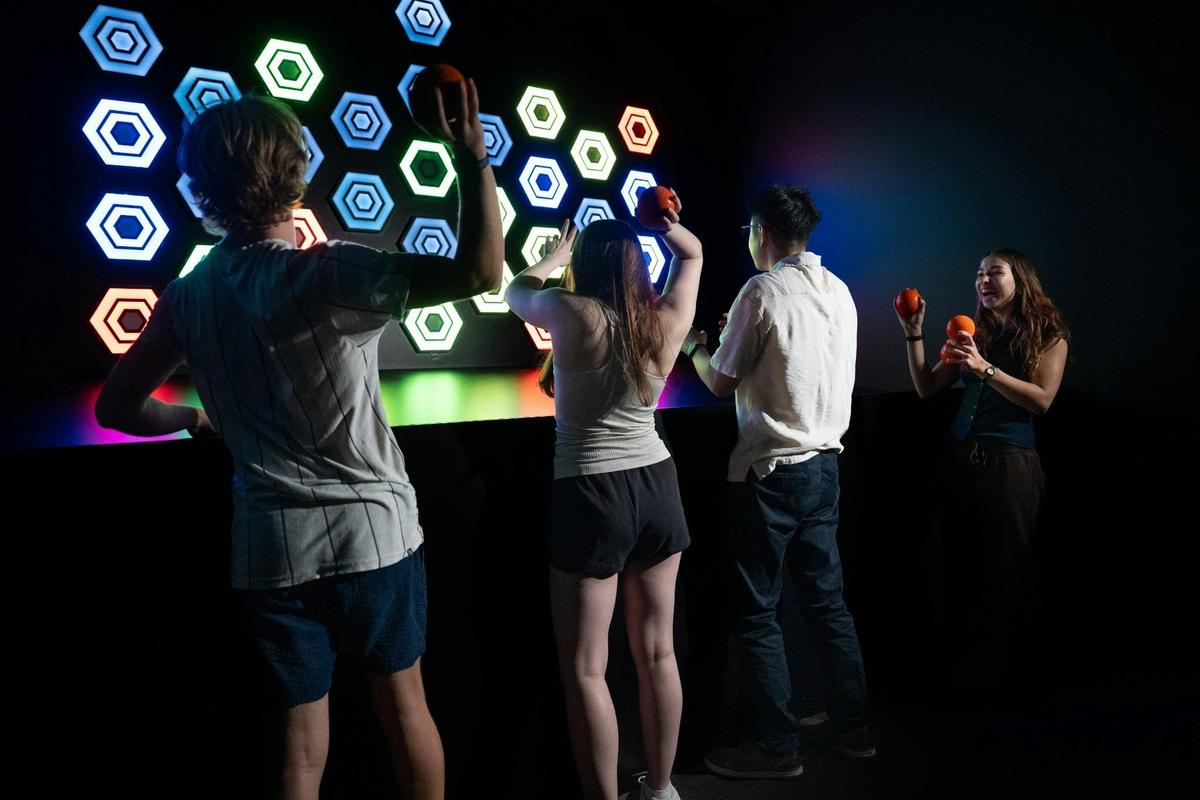 Friends enjoying an exciting interactive ball-throwing challenge at Power Play Sydney.