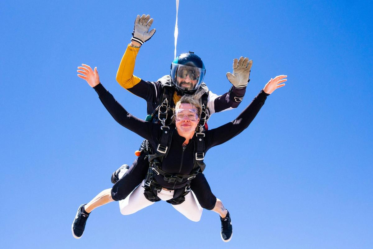 Tandem freefall with arms out against a clear blue sky