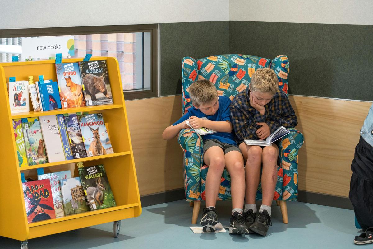 kids reading in  the storytime chair in the library kids area.