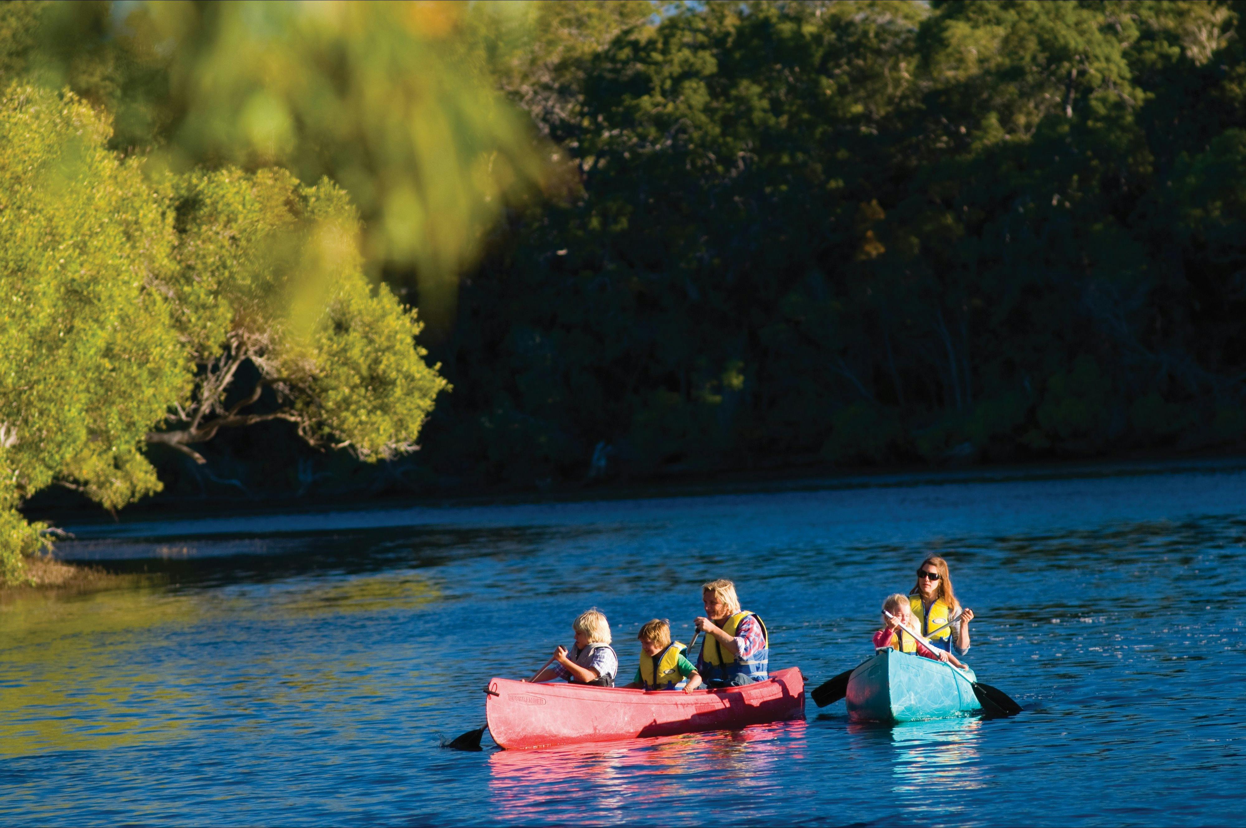 Two canoes with people in them on a river