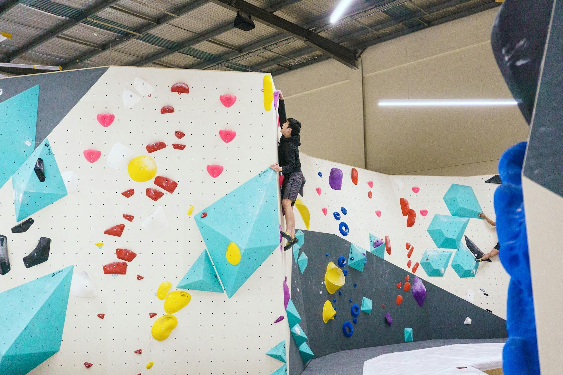 a climber is reaching the top hold of a climb & smiling