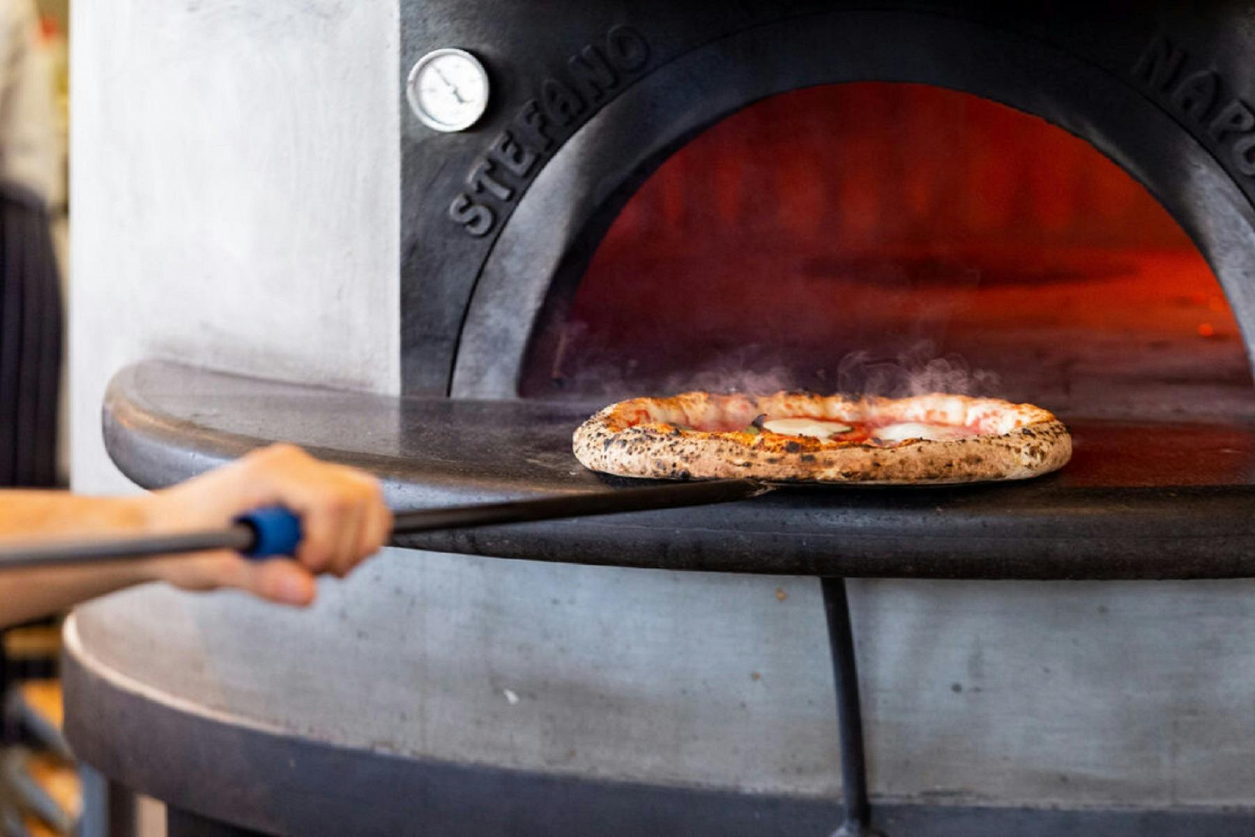 Woodfired pizza coming out of oven