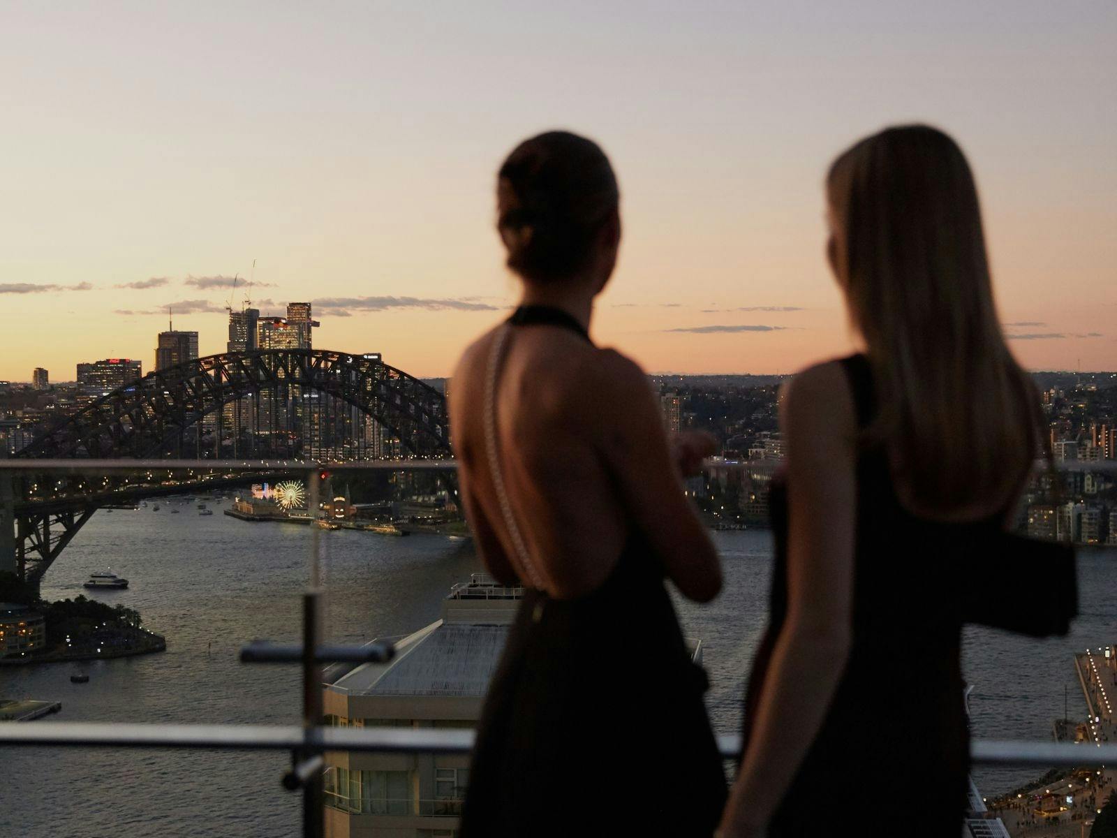 2 females looking over Sydney Harbour with the Harbour Bridge in the background