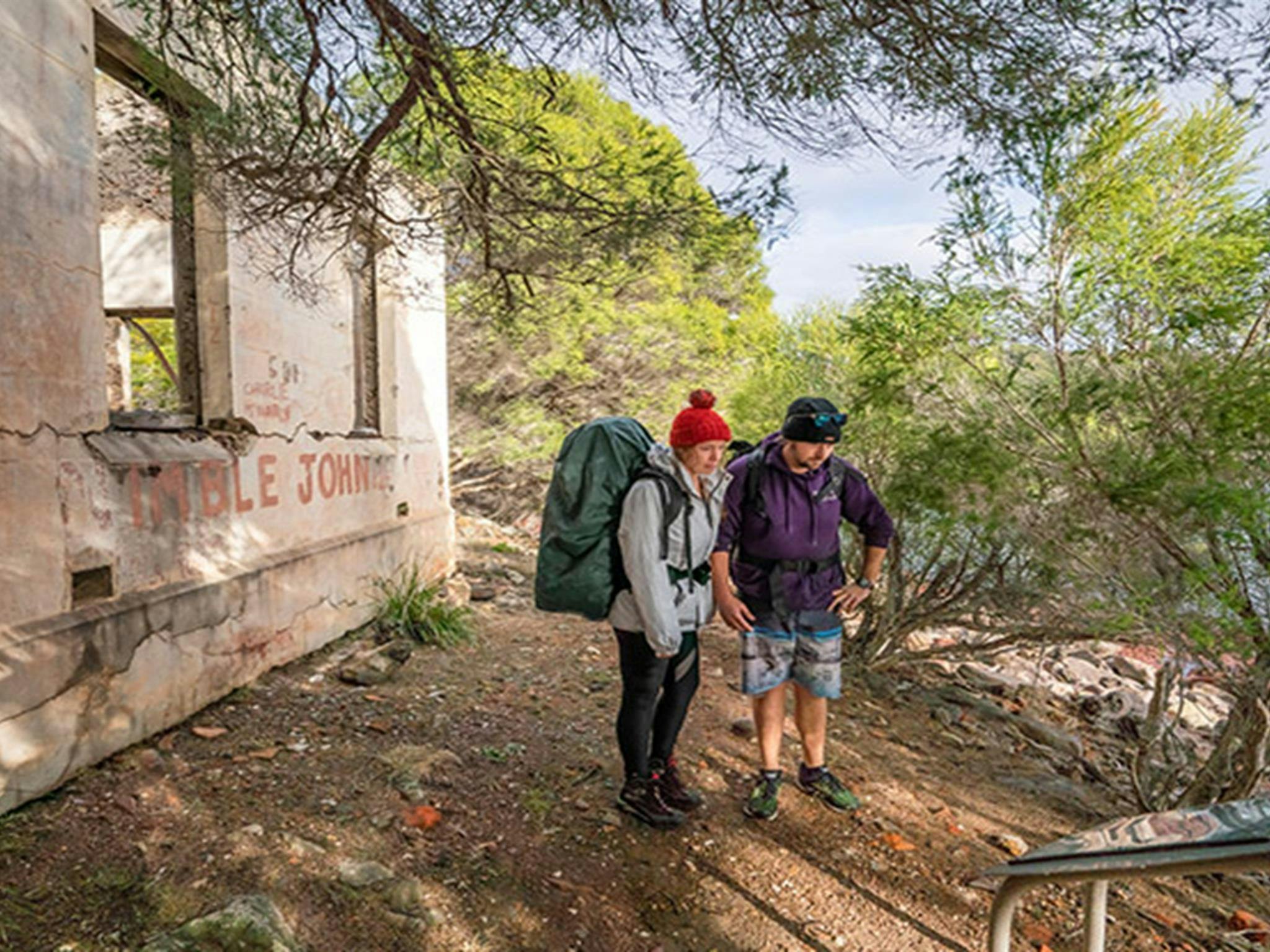People doing the Light to Light walk stop to read an information sign at Bittangabee Bay Storehouse.