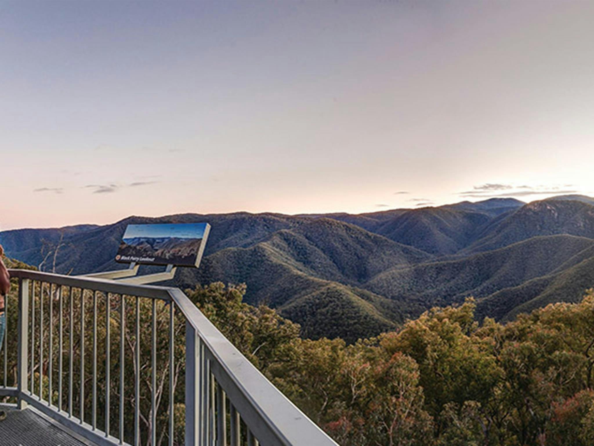 A woman stands next to a sign at Black Perry lookout, Kosciuszko National Park. Photo: Murray
