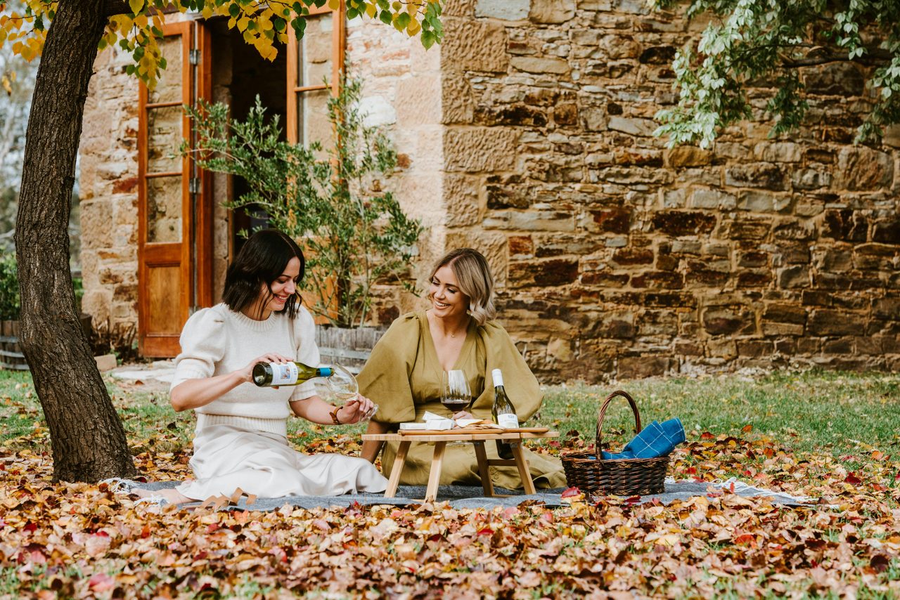 Visitors enjoying picnic hamper and wine in front of 180 year old 'Grafter Room'