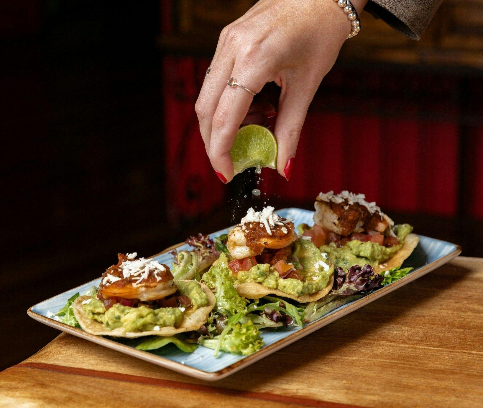 A crunchy tostada topped with layers of fresh guacamole, prawns, feta and that burst of lime.