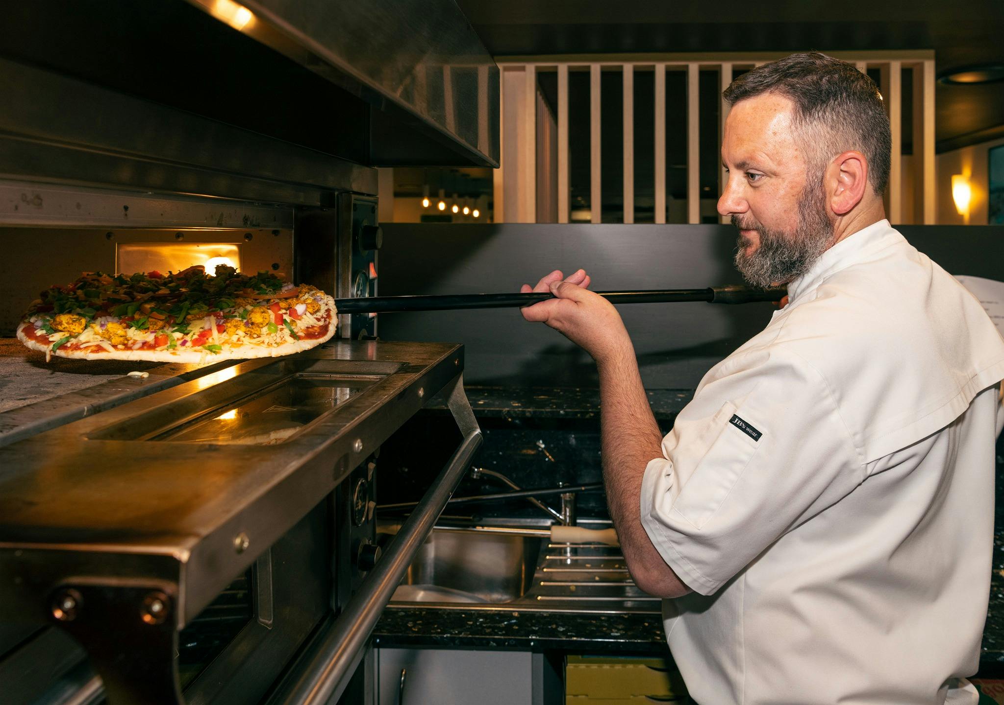Chef Frank getting a pizza from the oven