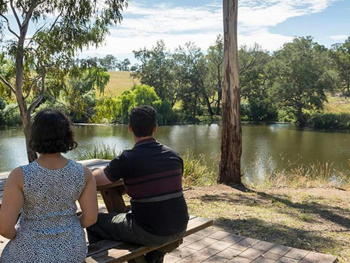 2 people resting at a picnic table at Blue Hole picnic area. Photo: Leah Pippos &copy; DPIE