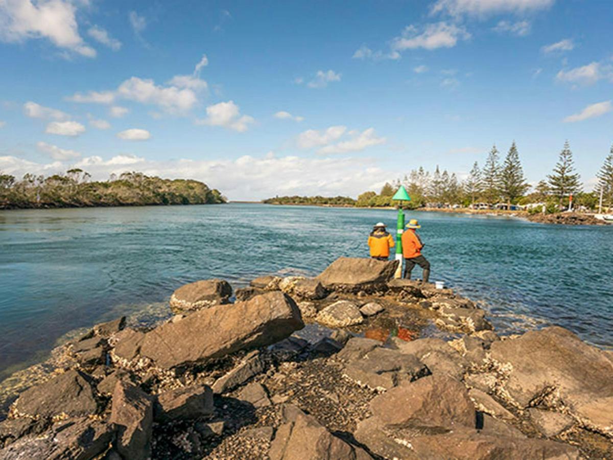 2 people fishing on the rocks at Brunswick River picnic area in Brunswick Heads Nature Reserve.