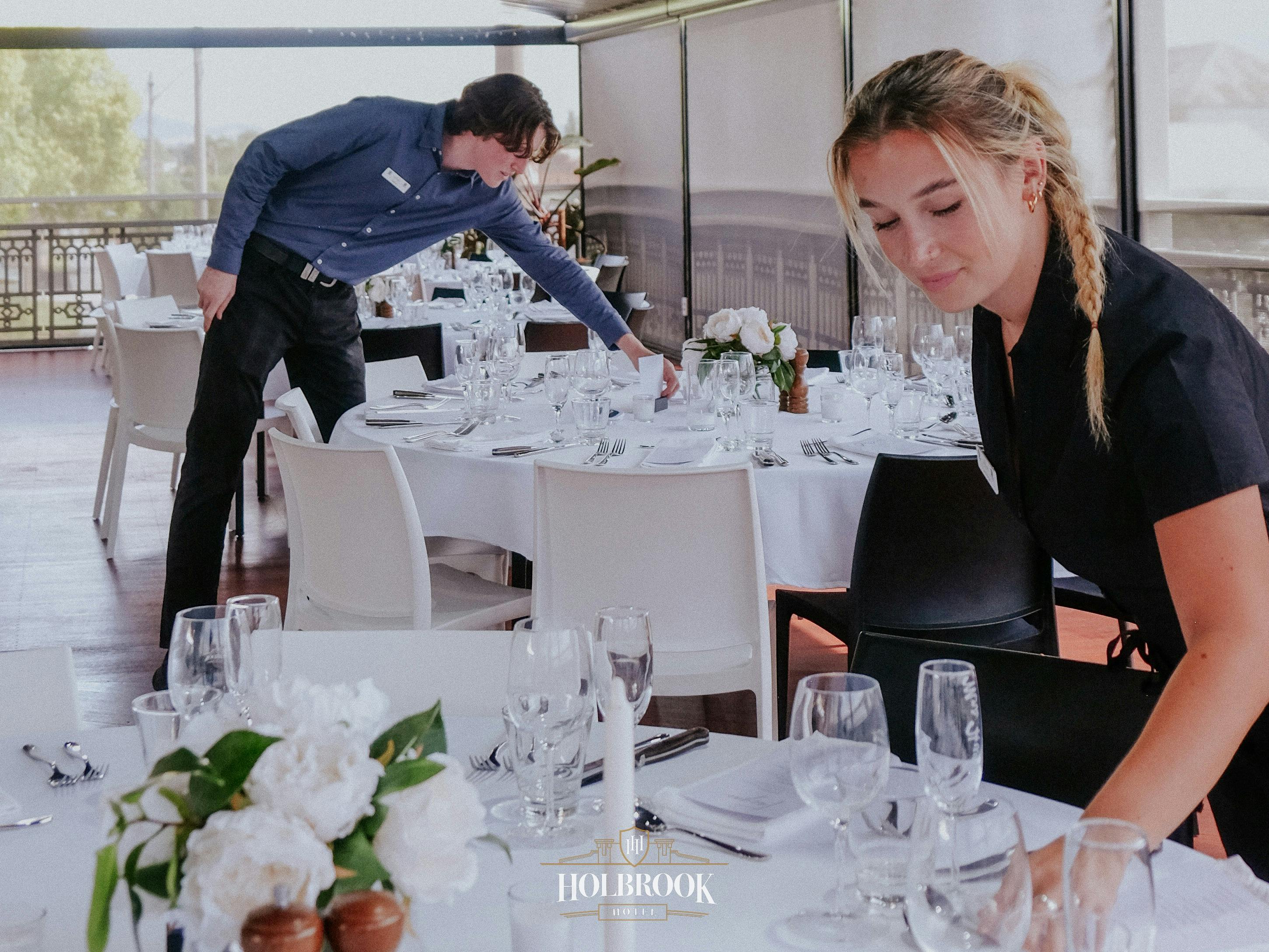 Two staff members setting dinner tables on the balcony