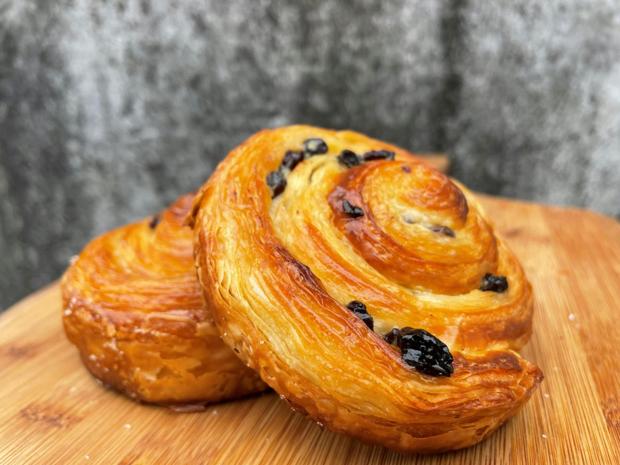 Two Raisin Scrolls fresh out of the oven displayed on a wooden board