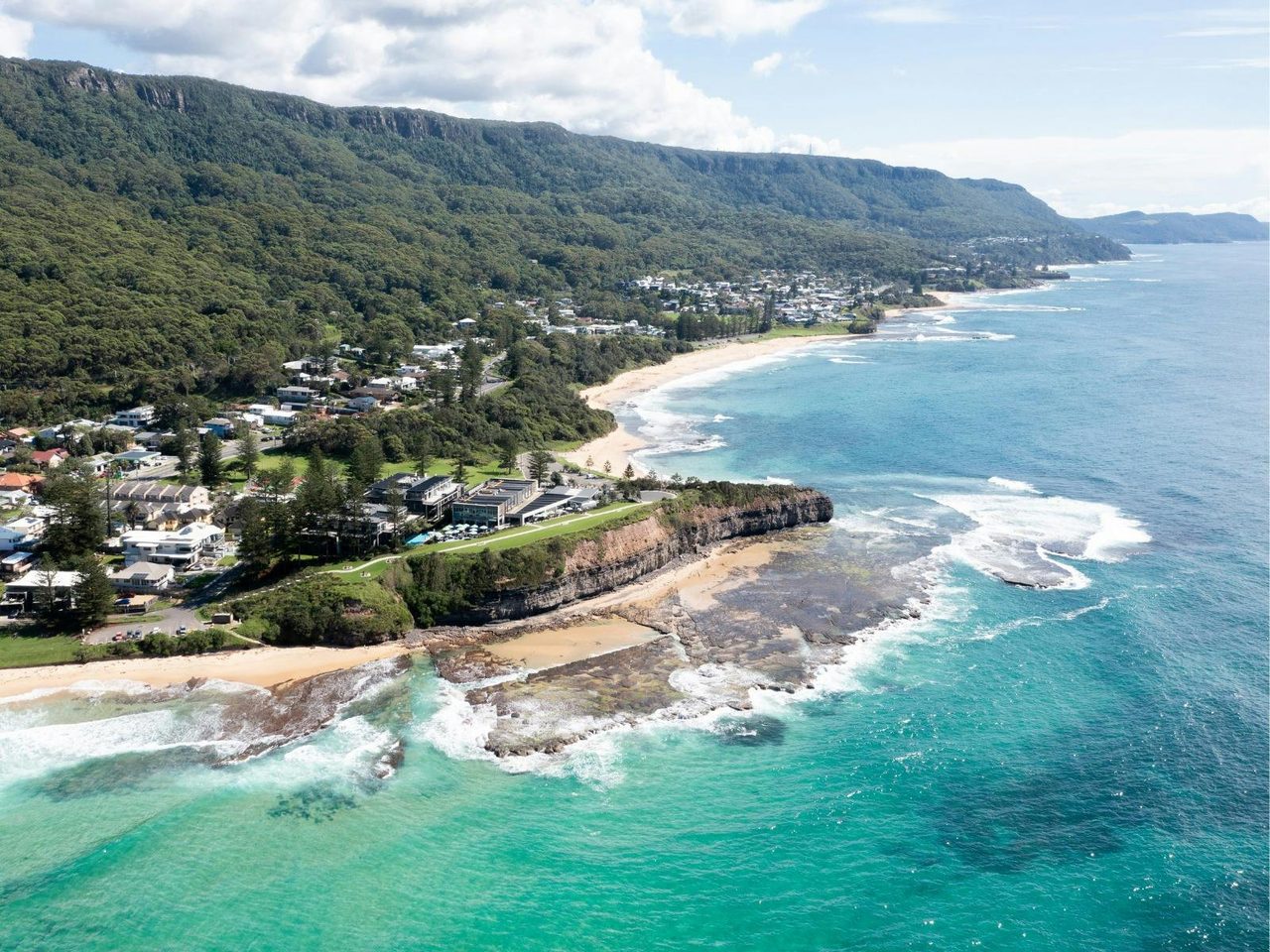 Aerial view of Headlands Austinmer Beach perched on the coastline with turquoise ocean.