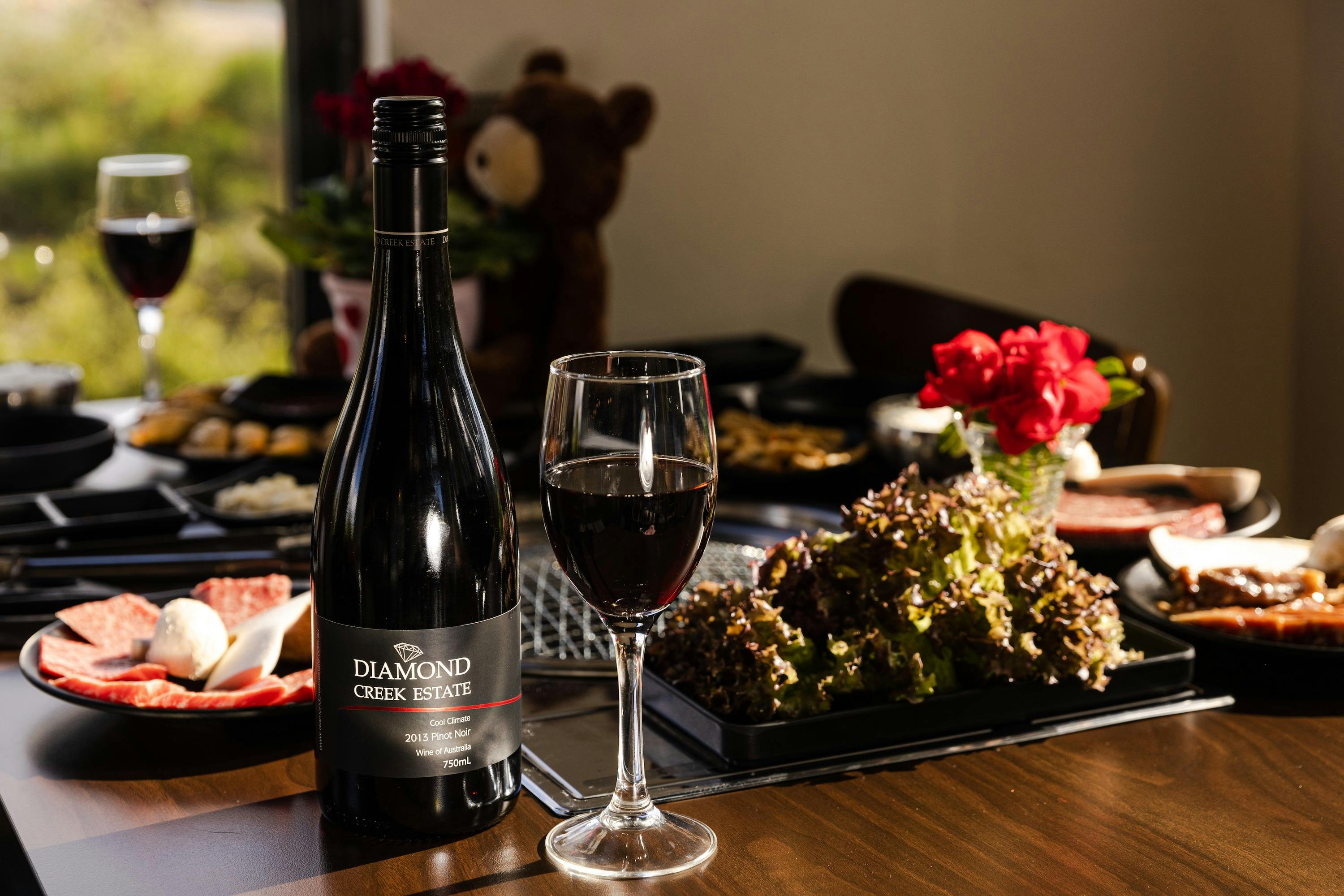 Bottle of 2013 pinot noir australian wine on bbq table with Wagyu Beef and complimentary side dishes