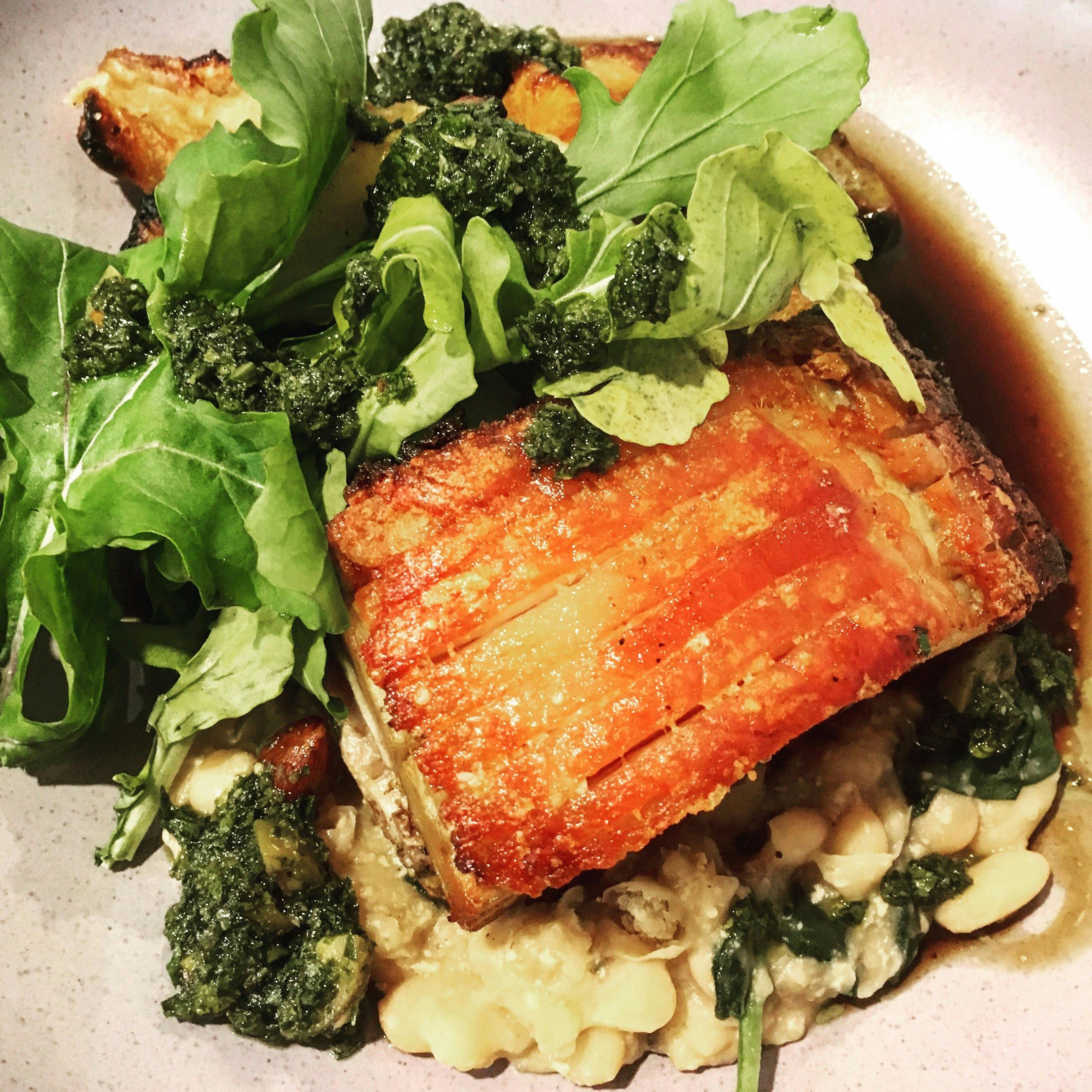 Milk braised pork belly with white beans, winter vegetables,  rocket, gremolata