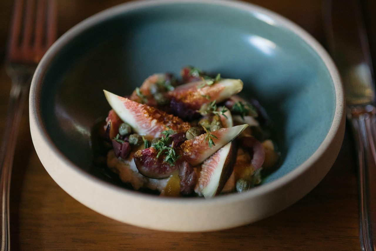 A restaurant dish featuring our estate grown figs, house made straciattella, and garden produce
