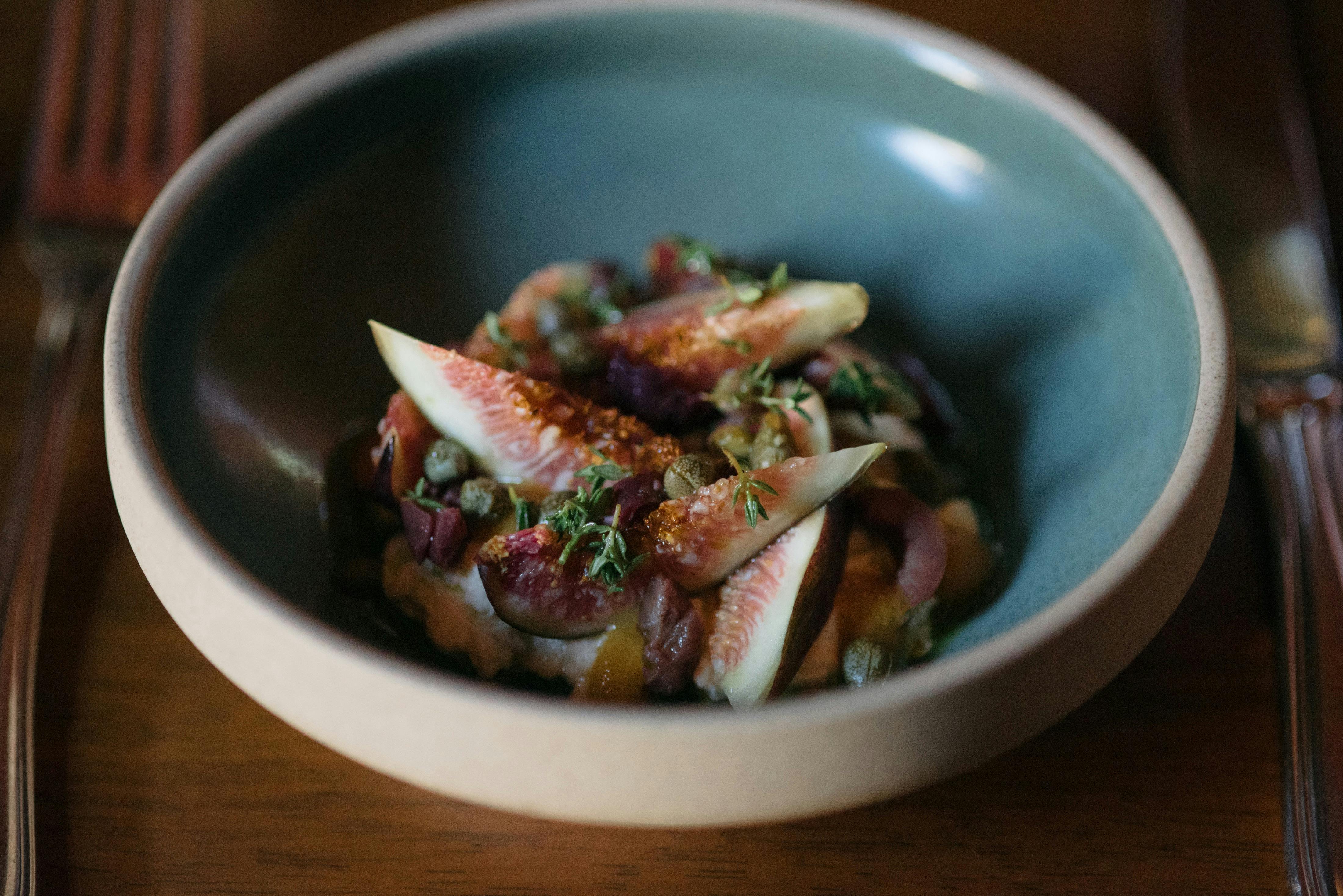 A restaurant dish featuring our estate grown figs, house made straciattella, and garden produce