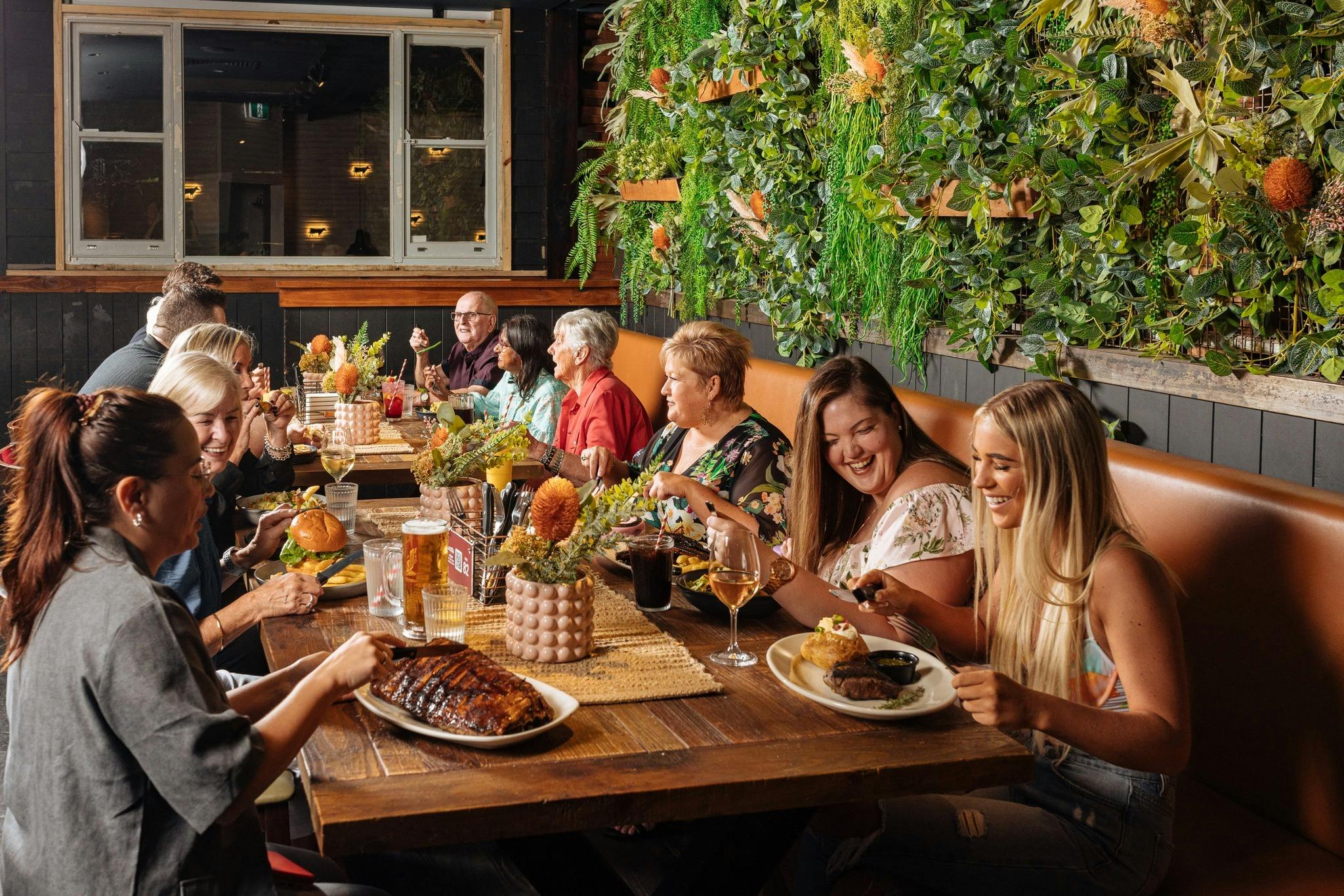 group of people sitting at a table eating drinking and smiling in Outback Steakhouse
