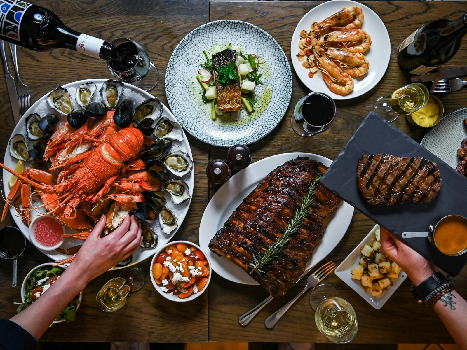Flat lay of Searock Grill menu items including Ribs, Seafood platter, fish, steak and prawns