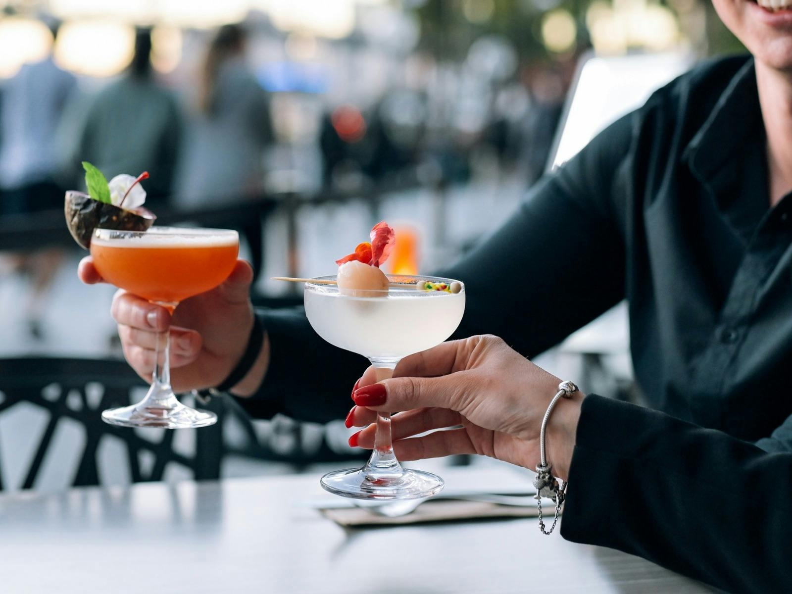 couple cheering a round of cocktails one orange with passionfruit and one with lychee