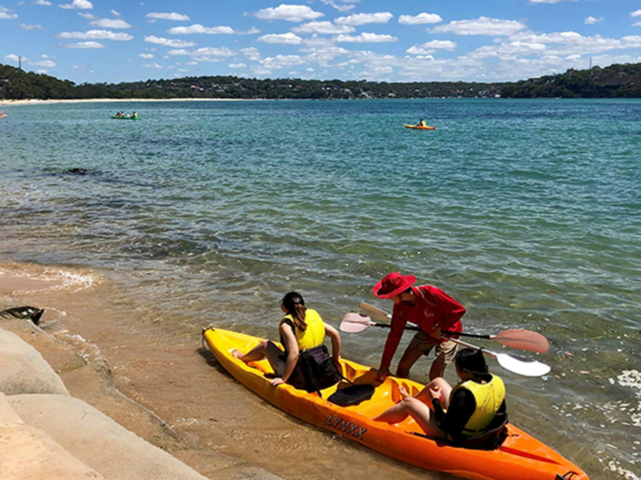 People being helped into a kayak in ocean, at Bonnie Vale picnic area. Photo: OEH/Natasha Webb