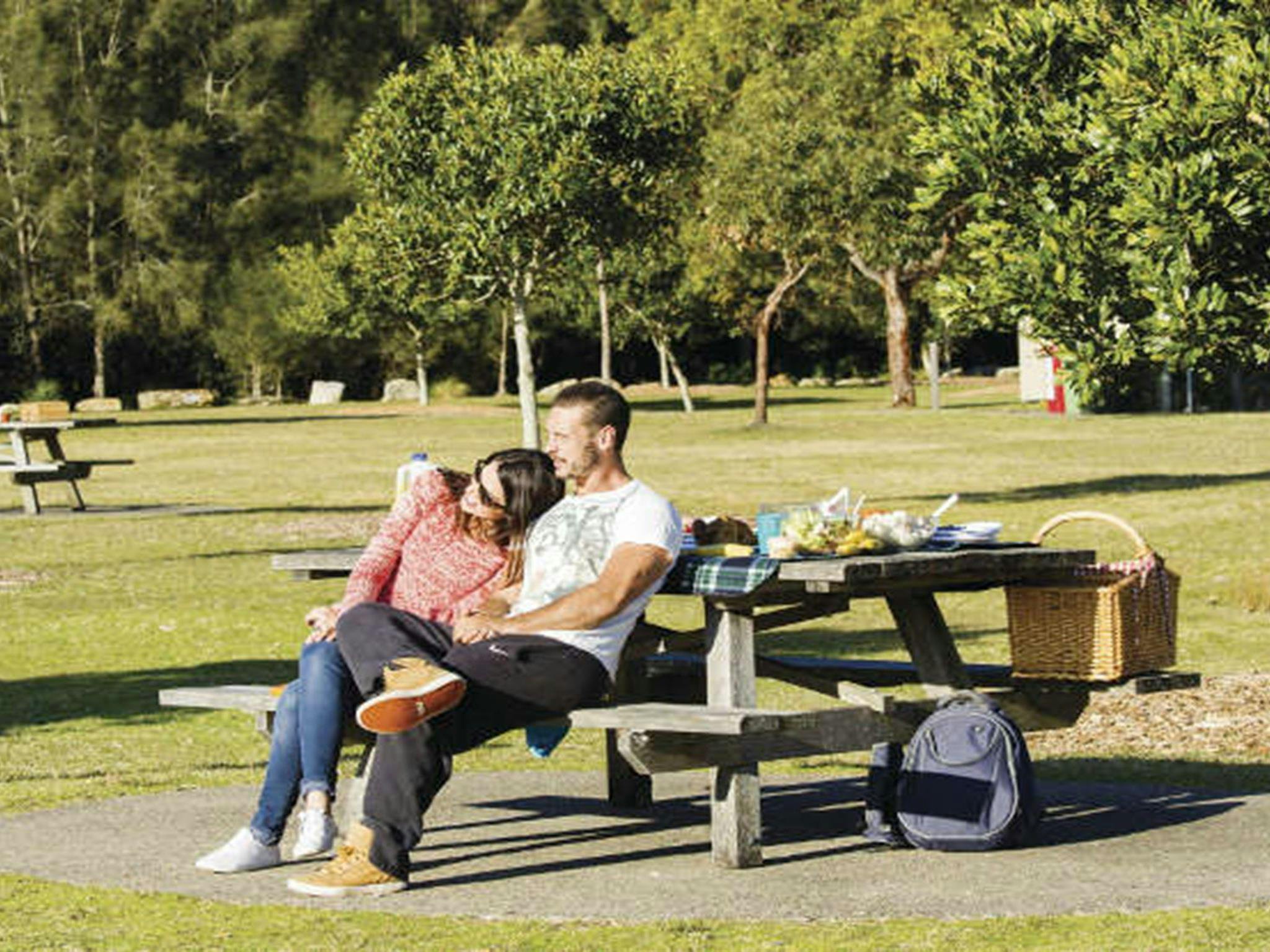 A couple enjoying the view from a picnic table at Bonnie Vale picnic area in Royal National Park.