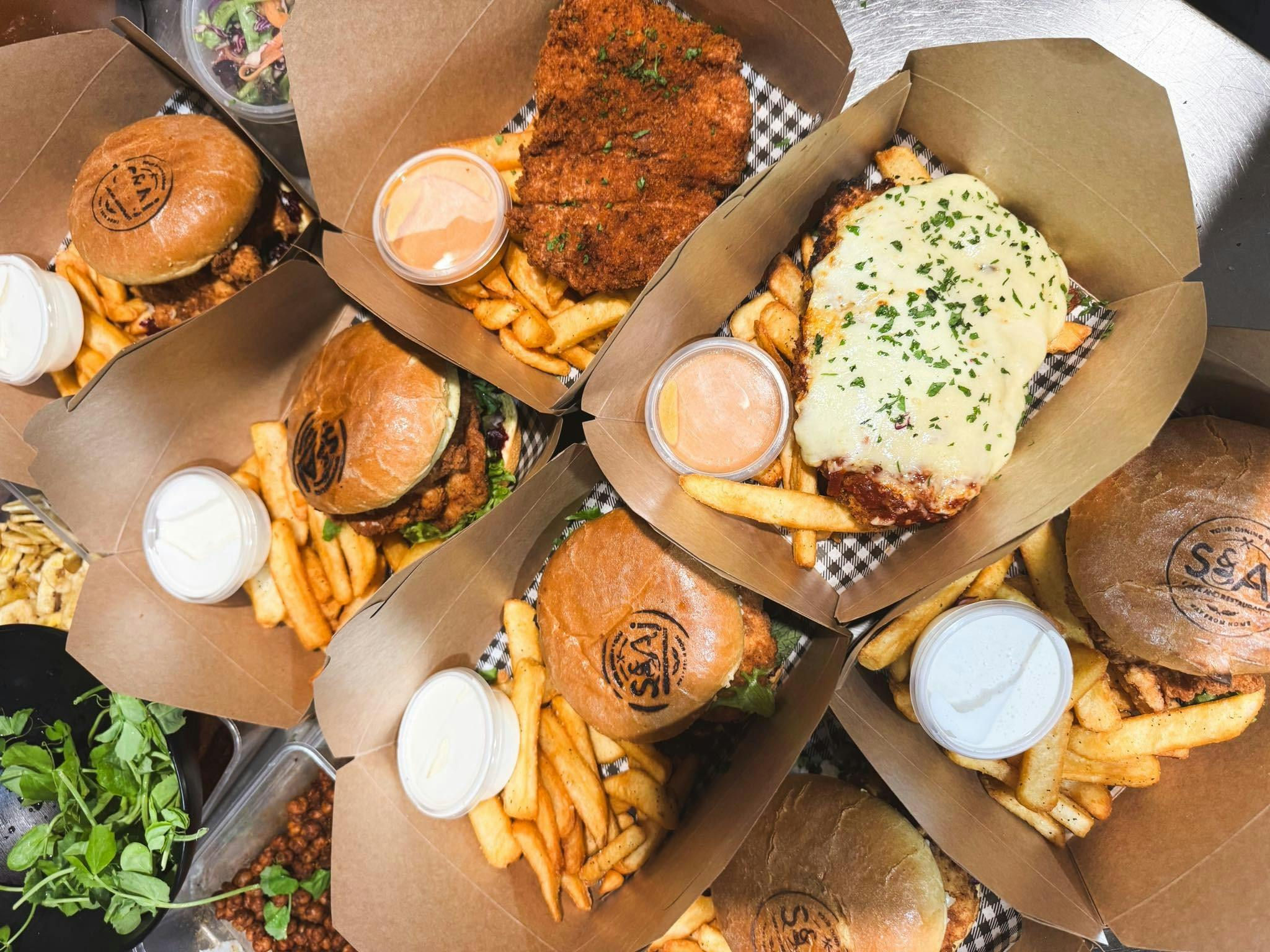 Large takeaway order of burgers, schnitties and chips with sauces.